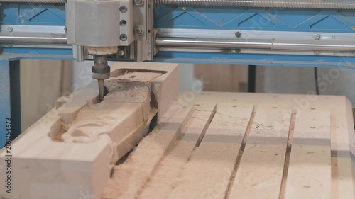 Wooden furniture factory and manufacture. Close-up of a multi-spindle CNC router machine milling intricate carved decorative patterns into wooden workpieces in a furniture manufacturing workshop.