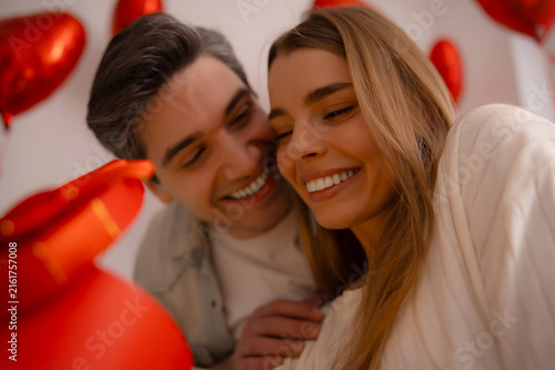 Foto Affectionate man kissing smiling woman on cheek on Valentine's Day