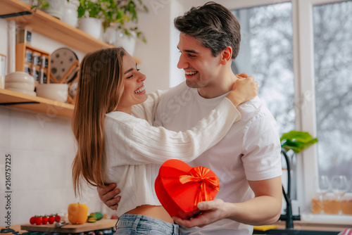 Фотография Smiling couple sharing affectionate look with heart-shaped gift