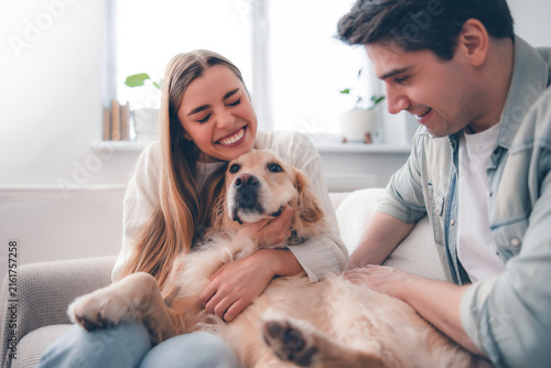 Canvastavla Happy woman hugging golden retriever as partner pets dog at home