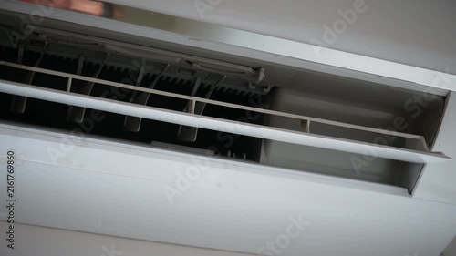 Air conditioner vent and dusty cooling unit.
A close-up view shows the open outlet and adjustable louvers of a wall-mounted split air conditioner with visible dust.