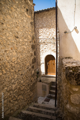Little pedestral road with staircase and door on a sunny day in the charming village of Castel del Monte, Abruzzo, Italy.