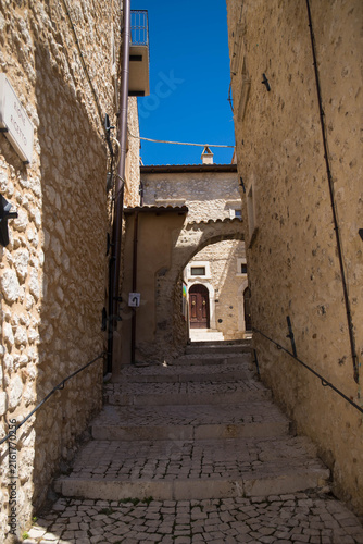 Little pedestral road with stairs and arch on a sunny day in the charming village of Castel del Monte, Abruzzo, Italy.