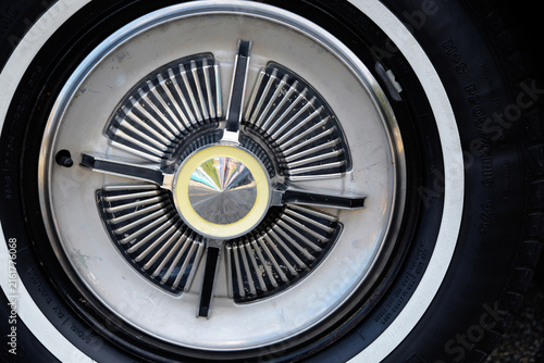 Canvastavla A vintage whitewall tire features a detailed chrome hubcap with radiating fins and a central spinner cap