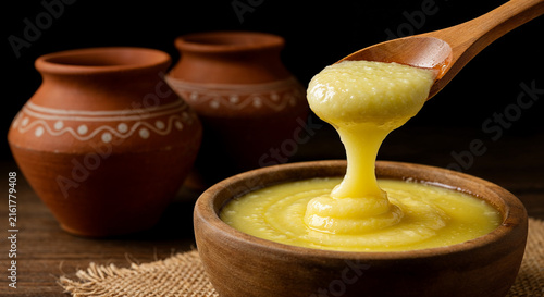 Pure organic ghee clarified butter pouring into a traditional clay pot