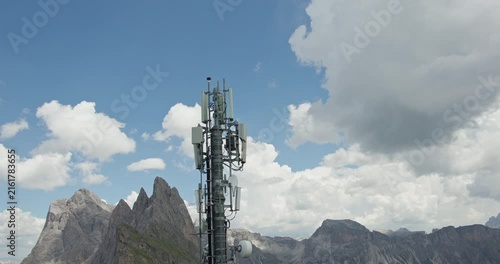 Mobile communication tower against rugged Dolomite mountains and dramatic summer clouds in the Italian Alps