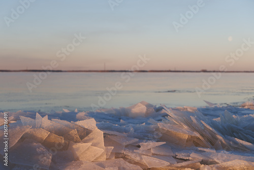 Cuadro en lienzo Close up scenery of broken ice shards and crystals on a northern coast covered with pastel golden and pink twilight sun light