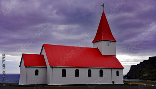 Fotografie A traditional white church with a vibrant red roof and steeple stands along the