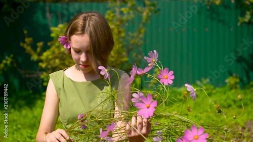 Close-up portrait of young Teenage girl touching and smelling flowering bush.