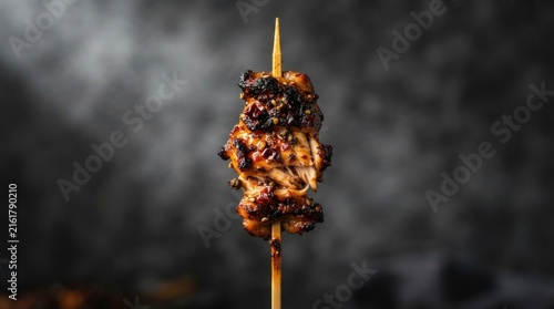 Charred chicken yakitori skewer on bamboo stick.
