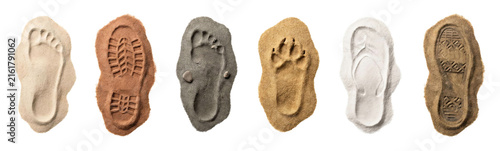 Various human and animal footprints imprinted in different colored sand, including a bare foot, boot sole, paw, and shoe prints, are arranged in a neat horizontal row