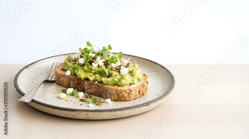 Gourmet Avocado Toast topped with Feta Cheese, Pumpkin Seeds, and Microgreens on Sourdough Bread