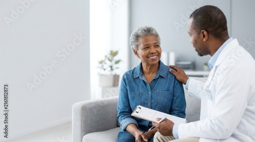 A professional doctor talking with an elderly African patient in a clinical setting.