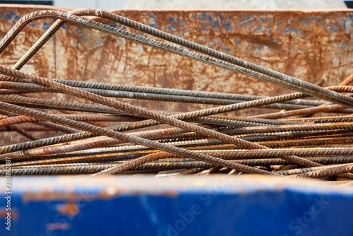 Fotografie Pile of rusty rebar bars creating a textured pattern inside a metal skip