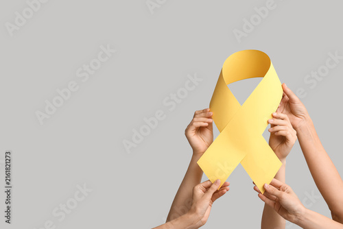 Obraz na plátne Cancer awareness and support, group of hands holding a yellow ribbon for childho