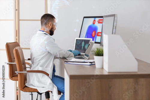 Male doctor analyzing scientific data at desk in laboratory, back view