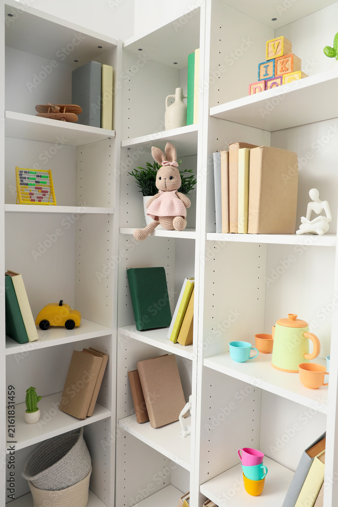 Naklejka premium White bookshelf with toys in childrens room