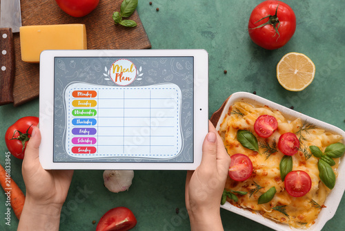 Young woman using meal plan app on tablet computer on green grunge background