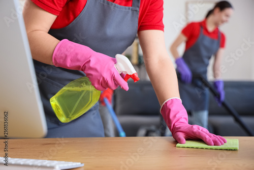 Female janitor cleaning desk in office, closeup