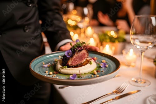 Waiter serving gourmet dish at restaurant dinner event with candle lights
