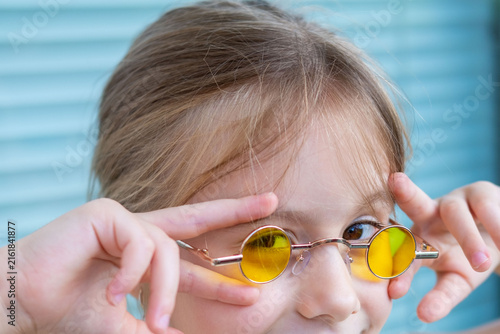 Obraz na płótnie little clever girl yellow round sunglasses, funny facial expression, smart profe