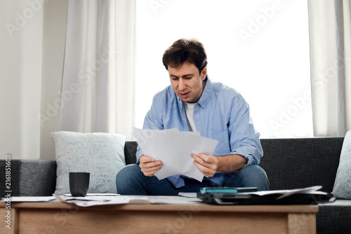 Fotografía Stressed man reading overdue utility bills at home