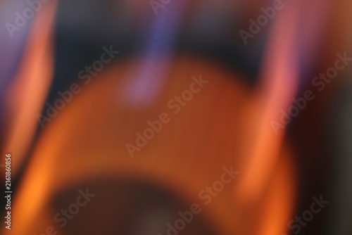 Close-up of a hand holding a glass of beer with blurred orange and purple lights background