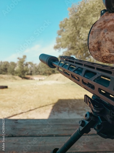 фотографія Sniper rifle with suppressor and bipod on firing range bench