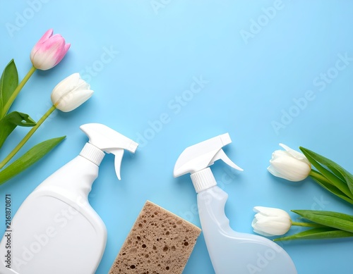 Cleaning supplies with tulips on a blue background, top down view