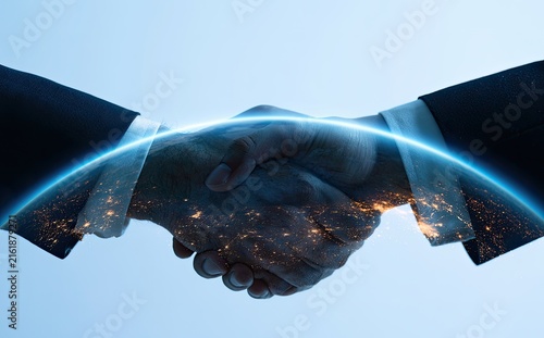Two business people shaking hands, superimposed over a glowing Earth