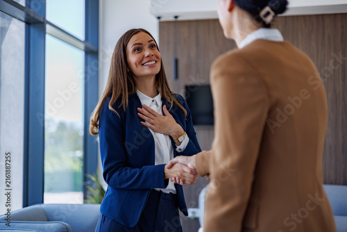 Businesswoman expressing gratitude during handshake with partner, celebrating successful partnership agreement in office