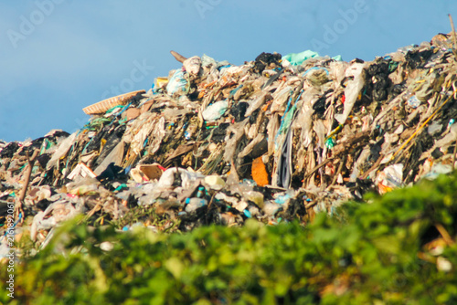 Large pile of garbage and plastic waste at open landfill site under blue sky	