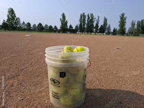 bucket of softballs on a field