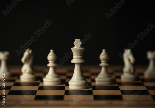 Принти на полотні white chess pieces aligned on wooden board, on black background