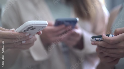 Multiple hands holding modern smartphones, people looking at screens, soft blurred background, concept of social media, messaging and everyday mobile technology use.