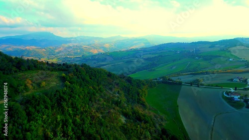 Mystical aerial truck left pan right shot from Santa Vittoria in Matenano, powerful views of the glorious Sibillini mountains, roads, meadows, thickets, hills full of vegetation, and unreal sunlight