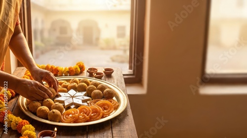 Woman Arranging Traditional Indian Sweets on Brass Plate for Festival