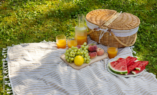 Obraz na płótnie Summer Picnic Basket with Fresh Fruit and Orange Juice in Green Garden