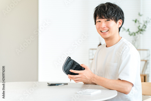 Foto A young Asian man opens his wallet in his living room.