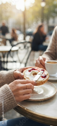hand holding a bagels and cup of coffee at the cafe in the morning
