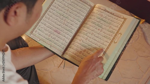 Close-up of a Muslim reading the Holy Quran and following Arabic verses with a finger in focused study. Islamic education, spiritual devotion, faith, worship, religious learning, and sacred scripture 