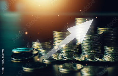 Stacked coins with a bold upward arrow symbolize investment growth, rising profits, financial success, wealth building, savings, business expansion, and positive market performance.