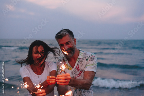 Принти на полотні Couple celebrating with sparklers at the beach