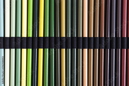 close-up of green and brown colored pencils neatly lined up in pencil case, concept of creativity, drawing, education and art supplies