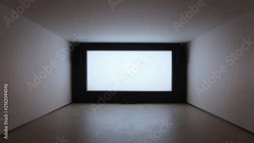 Minimalist gallery room projection screen glowing in a dark wall inset