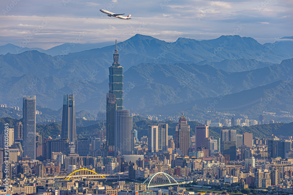 Obraz premium Passenger aircraft flying above Taipei 101 and the city skyline in Taiwan