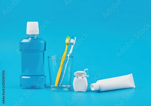 Dental hygiene products including mouthwash, toothbrushes, floss, and toothpaste on a blue background