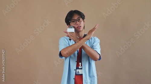 Young Asian male reporter holding microphone and making rejection gesture by crossing his arms in studio