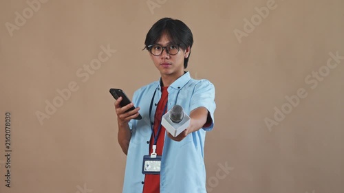 Asian male reporter holding smartphone and extending microphone to ask question in studio setting