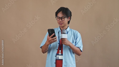 Asian male reporter holding microphone while pulling out smartphone and answering phone call studio